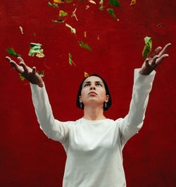 Full length portrait of young woman standing against red wall