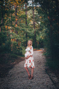 Portrait of woman standing by trees in forest