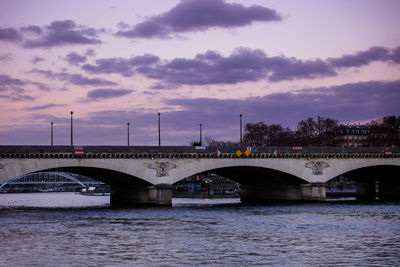 Bridge over river against cloudy sky