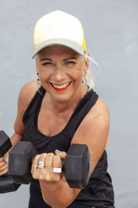 Portrait of fit senior woman with cool haircut holding dumbbells