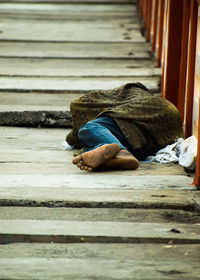 Rear view of man sleeping on street.