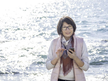 Smiling woman texting somebody on smartphone. active recreation on seaside. vacation on ocean coast. 