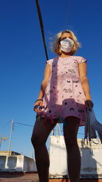 Low angle view of woman standing against clear blue sky