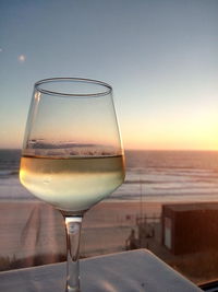 Close-up of white wine in wineglass on table against sea
