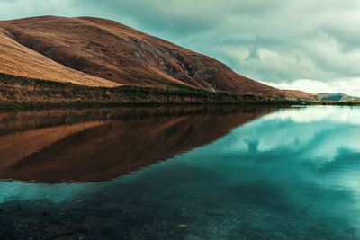 Scenic view of lake by mountain against sky