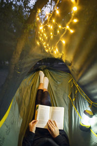 Camping in night forest with sparklers. woman lying in hammock