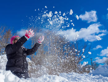 Girl flinging snow in winter.