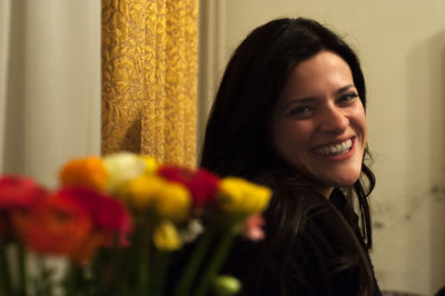 Portrait of smiling young woman by bouquet at home