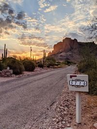 Road sign against sky during sunset