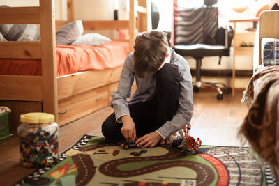 Boy teen plays with designer on the floor in real children's room