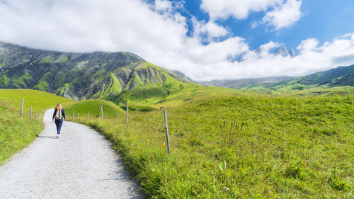 Rear view of woman walking on grassy landscape