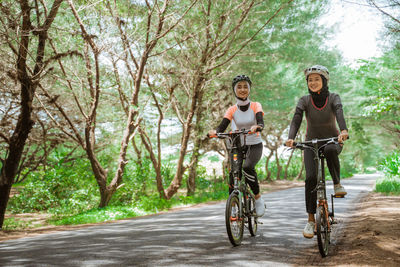 Rear view of woman riding bicycles on road