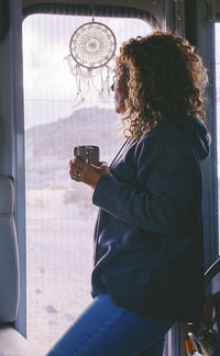 Rear view of man photographing through window