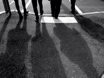 Low section view of four people crossing road