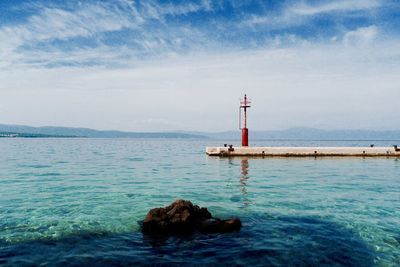 Low angle view of calm sea against cloudy sky