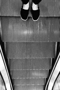 Low section of woman standing on escalator