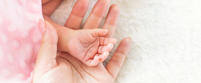 Mother holding hand of baby at home