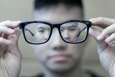 Close-up of hand holding eyeglasses on glass