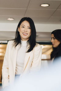 Smiling businesswoman standing amidst female colleagues during meeting in event