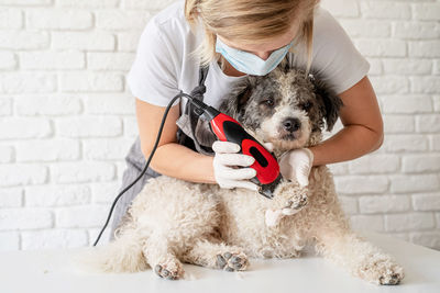 Woman holding dog against wall