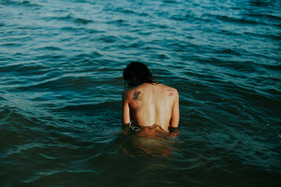 Shirtless lady swimming in sea