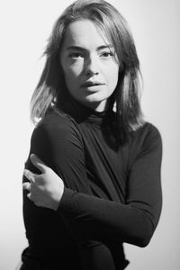 Portrait of young woman standing against white background