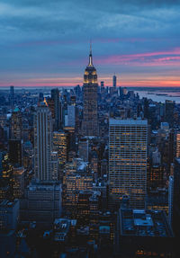 Aerial view of illuminated buildings against cloudy sky