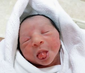 Close-up of newborn boy sticking out tongue