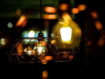 Illuminated light bulb hanging in darkroom