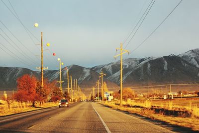 Country road passing by landscape against mountains