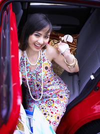 High angle portrait of young beautiful woman holding shopping bags while sitting in car