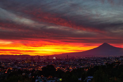 Aerial view of townscape against dramatic sky during sunset