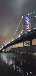 Illuminated bridge over river against sky at night
