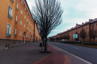 Empty road amidst buildings against sky