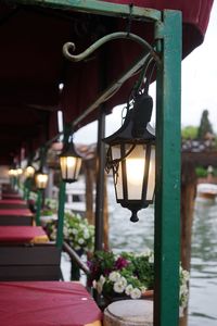 Close-up of illuminated lamp hanging on street by building