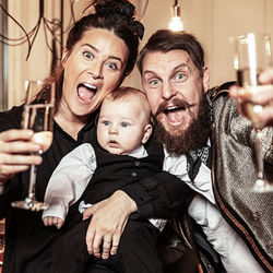 Portrait of cheerful parents with cute son holding champagne flutes at home