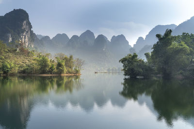 Scenic view of lake by trees against sky