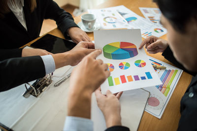 Midsection of business people working over graphs on table at office