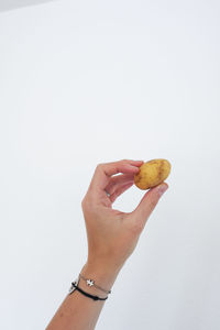 Cropped image of hand holding apple against white background