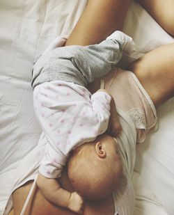 Directly above shot of woman sleeping with baby girl on bed