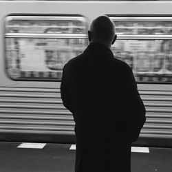 Rear view of man standing at railroad station