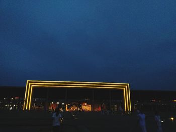 Silhouette people against illuminated building at night