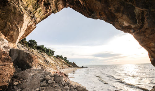 Rock formation on beach against sky