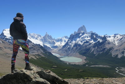 Rear view of person on snowcapped mountains against clear sky