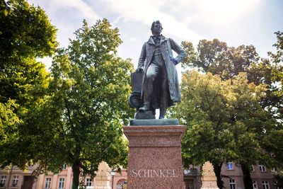 Low angle view of statue against trees and plants against sky