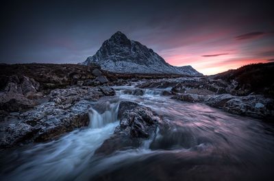 Scenic view of waterfall against sky during sunset