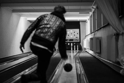 Rear view of man playing at bowling alley