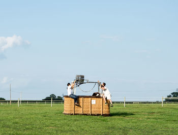 People standing by basket on field against sky