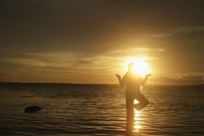 Silhouette people on beach against sky during sunset