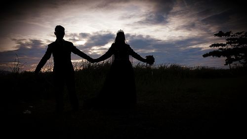 Silhouette people standing on field against sky during sunset